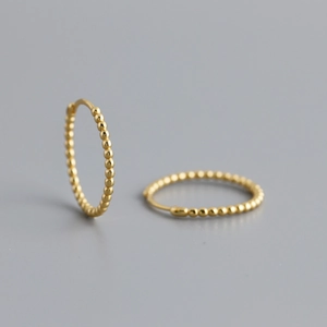 Macro shot of gold-plated S925 silver hoop earrings with textured beaded design details