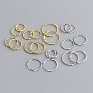 Macro detail of S925 sterling silver hoop earrings with beaded texture in gold and silver