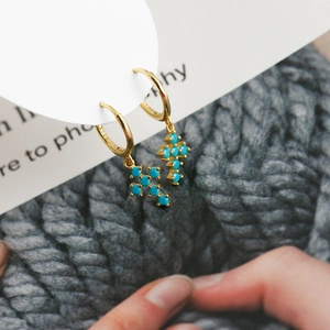 Détail des boucles d'oreilles créoles dorées en argent S925 avec pendentifs croix turquoise