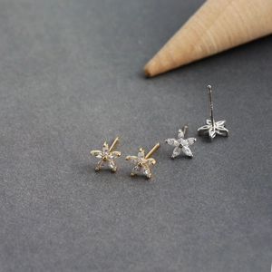 Dettaglio macro di orecchini a fiore in argento S925 con zirconi in oro e argento