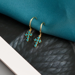Détail de boucles d'oreilles créoles dorées avec croix ornées de pierres turquoise