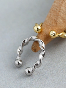 Macro shot of twisted s925 silver ear cuffs with smooth ball ends and gold plating