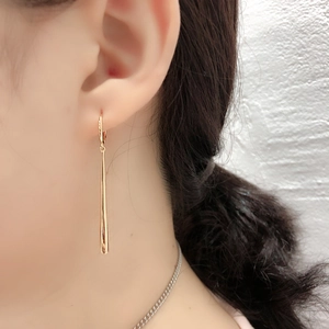 Close-up van elegante gouden druppeloorbellen bij een model met een glanzende finish
