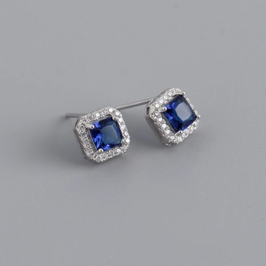 Macro detail of square blue zircon earrings with a sparkling diamond halo setting