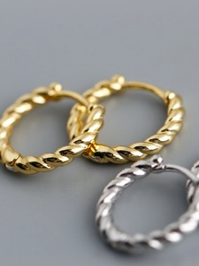 Macro view of twisted rope hoop earrings in polished gold and silver metallic finishes