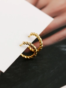 Macro shot of gold twisted rope hoop earrings showcasing detailed metallic texture