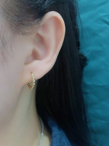 Close-up of golden s925 silver twisted hoop earring on model ear in vintage style