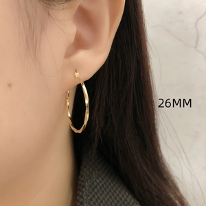 Macro-opname van een 26mm gouden gedraaide oorbel op een model met metallic glans