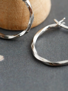 Macro-opname van gedraaide S925 sterling zilveren oorringen met hoogglans afwerking