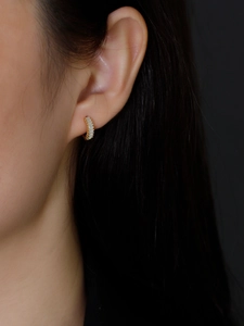 Close-up of golden S925 silver ear hoop with baguette-cut zircons on female ear