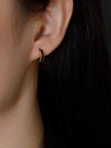 Close-up of gold hoop earring with black rectangular cut zircons on female model