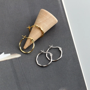 Detailopname van gedraaide oorringen in goud en zilver op houten standaard