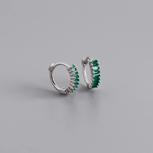Macro detail of silver earrings with emerald green baguette zircons in a channel setting
