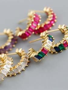 Close-up of gold-plated C-shaped earrings set with colorful rectangular zircons