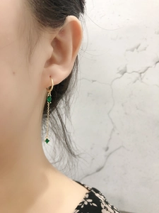 Primo piano di lunghi orecchini a nappa con zircone verde e argento s925 dorato