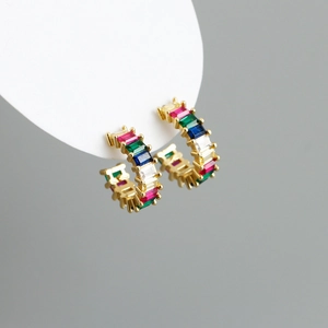 Detail of gold C-shaped earrings with colorful baguette-cut stones and rainbow crystals