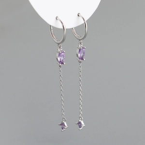 Dettaglio di orecchini pendenti in argento con nappe in zircone viola e punzone S925