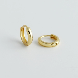 Dettaglio di orecchini huggie in argento sterling S925 dorato con marchio S925 inciso
