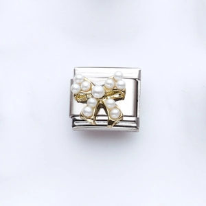 Makroaufnahme von italienischem Charm-Glied mit goldener Schleife und Perlen