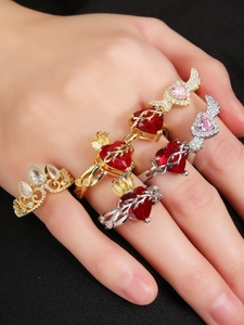 Detail of red heart gemstone ring and silver angel wing ring worn on fingers