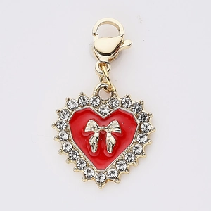 Pendentif cœur doré avec émail rouge, nœud et strass sur fond blanc immaculé