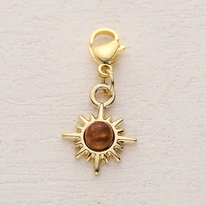 Close-up of a golden sun pendant with brown gemstone and lobster clasp for DIY jewelry