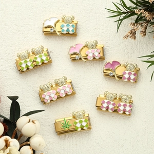 Set di 7 charm modulari in acciaio con orsetto e foglie per bracciali su sfondo beige