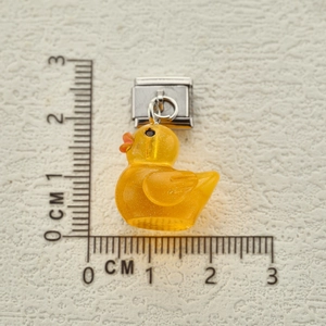 Detail of yellow glitter resin duck charm on stainless steel Italian link bracelet