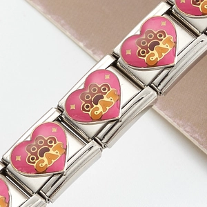 Vue macro d'un maillon modulaire en acier avec cœur émaillé rose et empreinte CAT