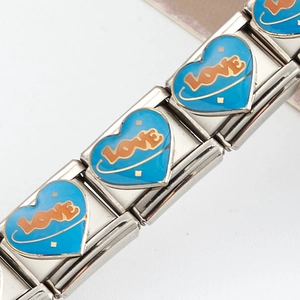 Détail macro du charme modulaire italien en acier inoxydable avec cœur émaillé bleu et LOVE