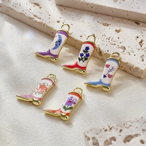 Five vintage boot-shaped enamel charms with moon and floral patterns on stone surface