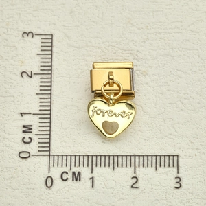 Dettaglio del ciondolo a cuore dorato con incisione forever e righello da 1,5 cm