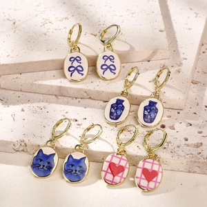Set of four vintage oval enamel earrings with floral, cat, and heart patterns on stone stand