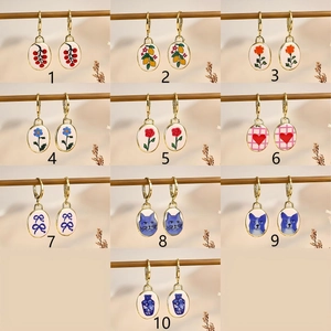 Collection of 10 vintage gold oval earrings with floral and cat illustration patterns