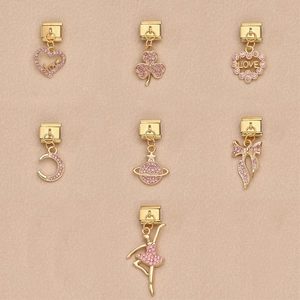 Detalle de dijes italianos con cristales rosas, diseños de corazón, luna y estrella