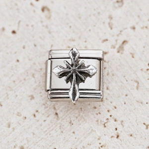 Close-up of a silver stainless steel Italian charm with a 3D embossed cross design