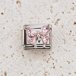 Macro detail of a silver charm with a pink faceted gemstone bow for modular bracelets