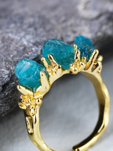 Macro view of blue raw apatite stones set on a branch-textured 18K rose gold ring band
