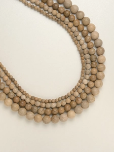 Macro detail of various sizes of natural camphor wood beads showing rich wood grain texture