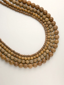 Macro shot of natural wood beads in four sizes showing fine wenge wood grain details