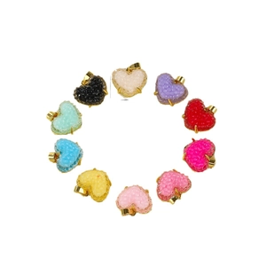 Pendentifs cœurs en résine colorée sertis d'or disposés en cercle sur fond blanc