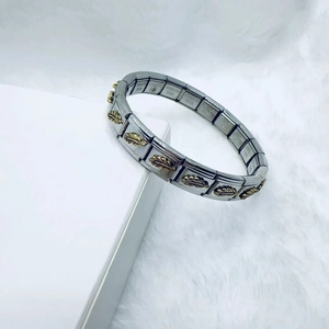 Bracelet italien en acier inoxydable avec plumes dorées sur un fond de fourrure blanche