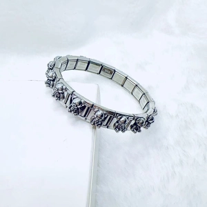 Close-up of stainless steel charm bracelet featuring a 3D teddy bear charm detail