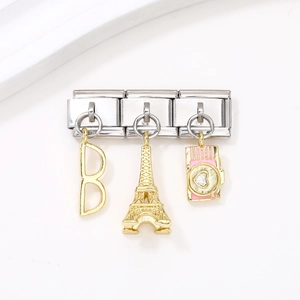 Détail des breloques en acier avec tour Eiffel dorée et appareil photo émaillé rose