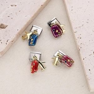 Italian charm link bracelet with colorful suitcase and gold airplane pendants on stone