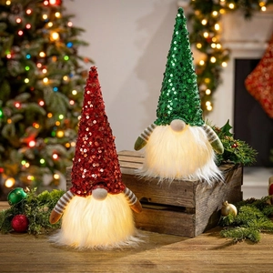 Close-up of glowing Christmas gnomes with LED lights and sequined hats on wooden surface