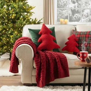 Festive red Christmas tree plush pillows and knit blanket on a white sofa decor