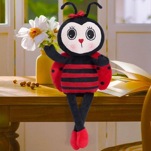 Cute ladybug plush toy with long legs and heart-shaped nose on a wooden desk background