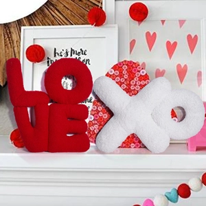 Plush red LOVE and white XO letter pillows set on fireplace mantle for home decor