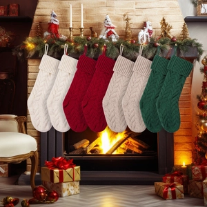 Set van 8 kabelgebreide kerstsokken in rood, groen, wit en beige bij de open haard